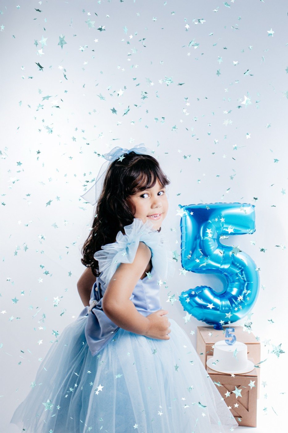 Menina entre confetes com balão do número 5