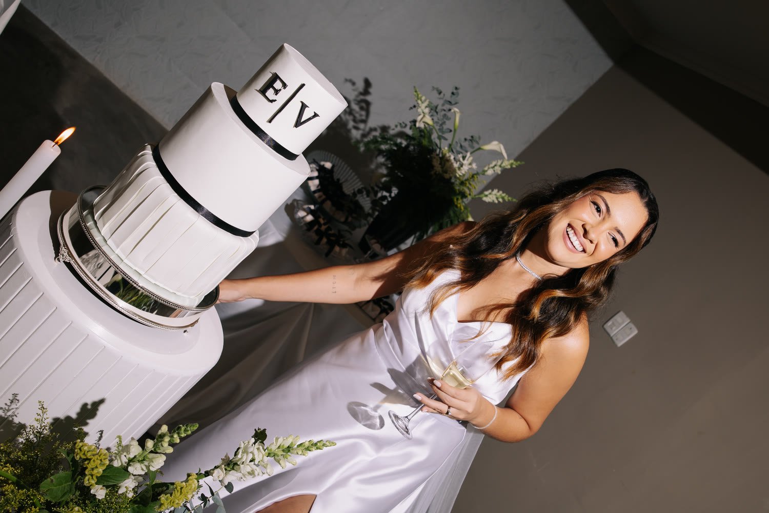 Noiva sorrindo ao lado do bolo de casamento