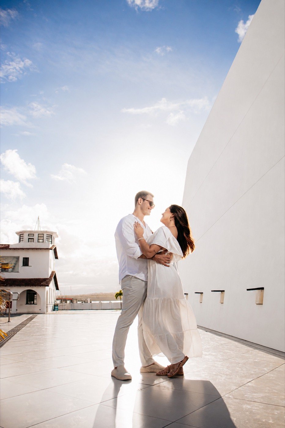 Casal abraçado junto a um muro branco